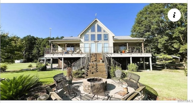 rear view of house featuring a fire pit, stairway, a lawn, and a patio