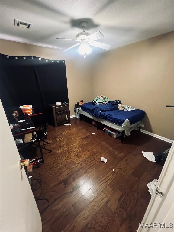 bedroom with hardwood / wood-style flooring, a textured ceiling, baseboards, and a ceiling fan