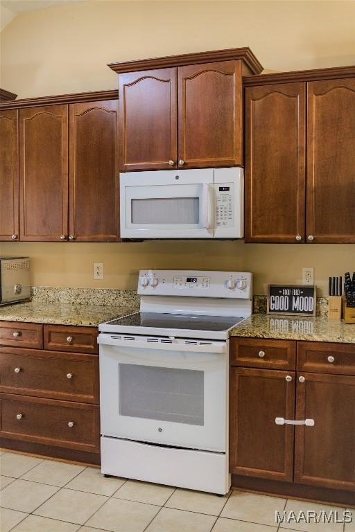 kitchen with white appliances, light tile patterned floors, and light stone counters