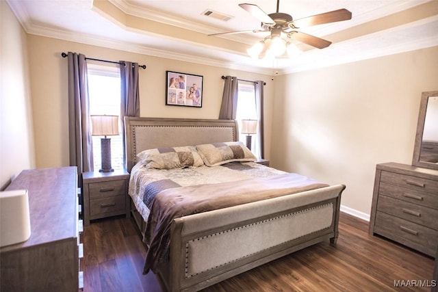 bedroom featuring a tray ceiling, visible vents, dark wood-type flooring, ornamental molding, and a ceiling fan