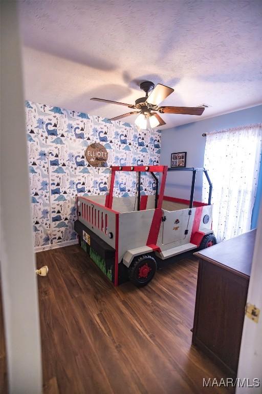 bedroom with a textured ceiling, a ceiling fan, and wood finished floors