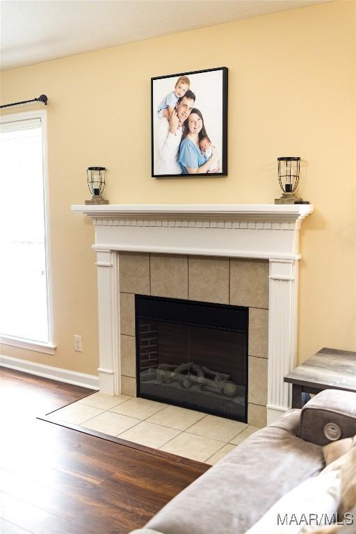 interior details with a tiled fireplace, baseboards, and wood finished floors