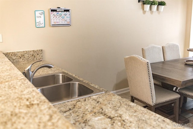 tiled dining area featuring a sink and baseboards