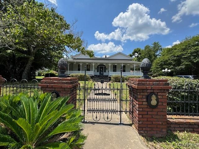 view of gate with a fenced front yard and a porch