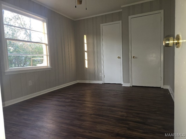 unfurnished room with ornamental molding, dark wood finished floors, baseboards, and ceiling fan