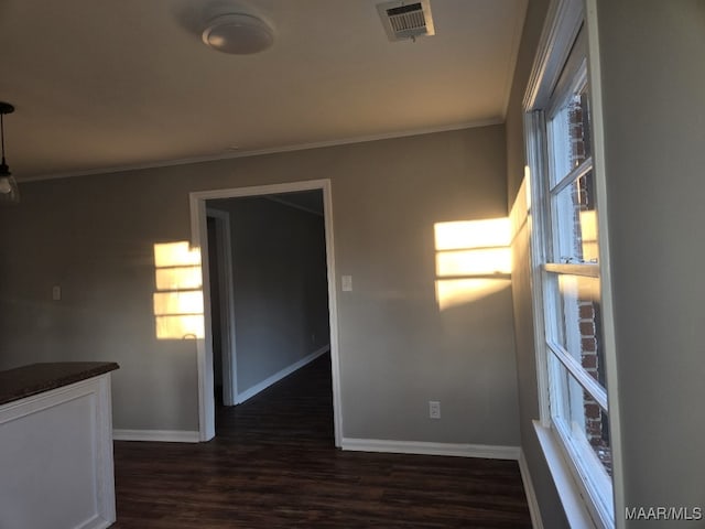 spare room featuring visible vents, ornamental molding, dark wood finished floors, and baseboards