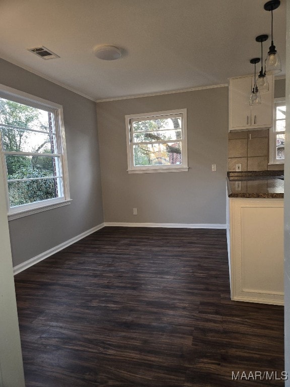 empty room featuring dark wood-style flooring, visible vents, crown molding, and baseboards