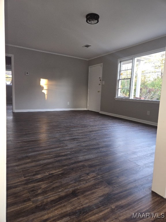 unfurnished living room featuring crown molding, visible vents, baseboards, and dark wood-style flooring