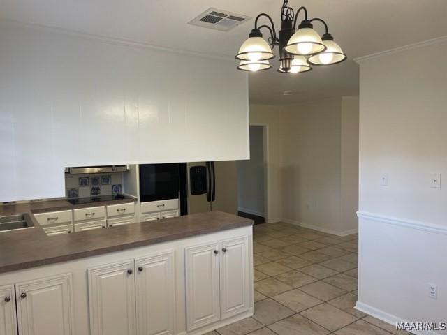 kitchen with pendant lighting, tasteful backsplash, dark countertops, visible vents, and white cabinetry