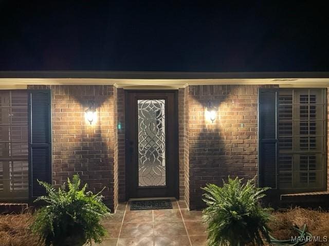 exterior entry at night featuring brick siding