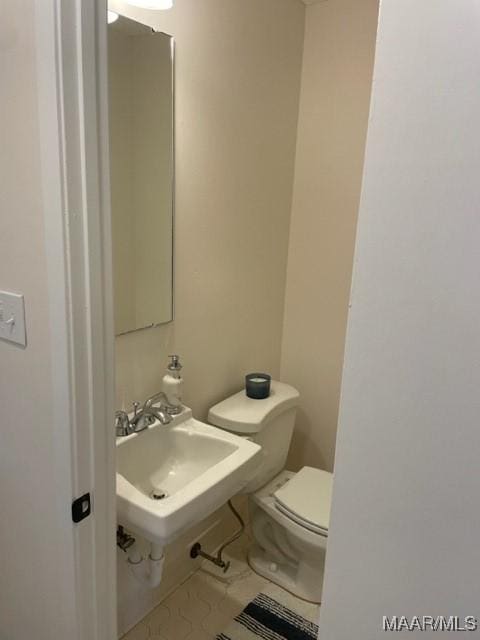 half bathroom with tile patterned flooring, a sink, and toilet