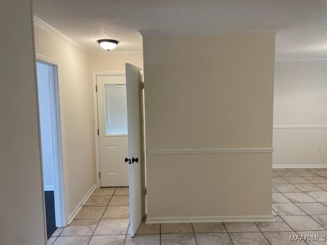 hallway featuring light tile patterned floors, baseboards, and crown molding