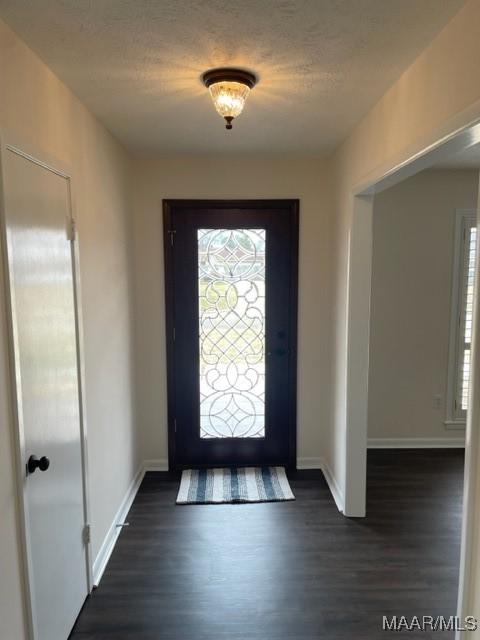 foyer featuring a textured ceiling, dark wood finished floors, and baseboards