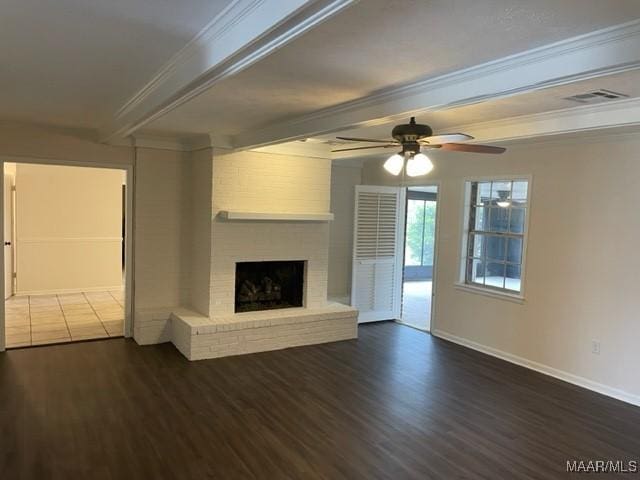 unfurnished living room featuring wood finished floors, visible vents, baseboards, a brick fireplace, and beamed ceiling