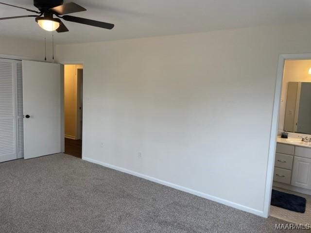 unfurnished bedroom with light carpet, a closet, baseboards, ensuite bath, and a sink