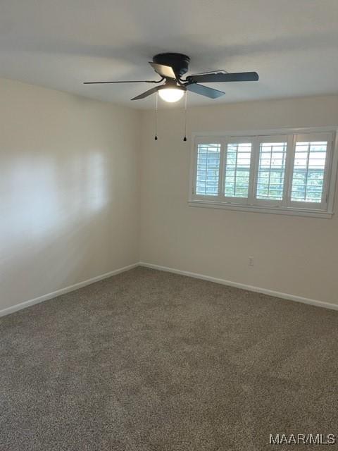 carpeted spare room featuring ceiling fan and baseboards