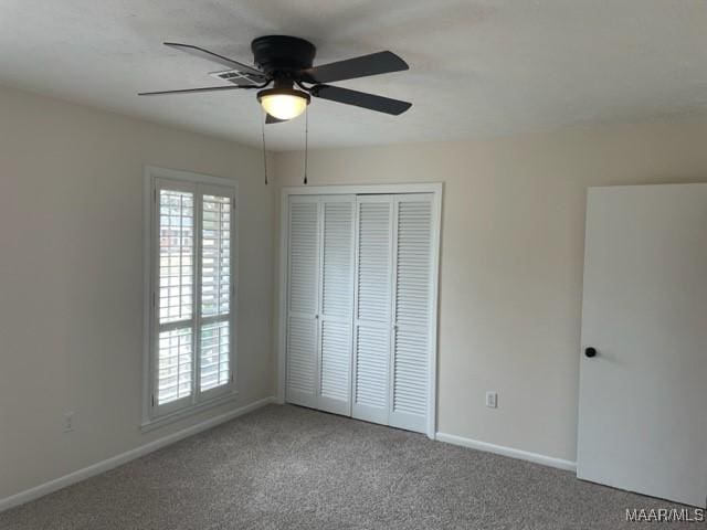 unfurnished bedroom featuring ceiling fan, a closet, baseboards, and carpet flooring