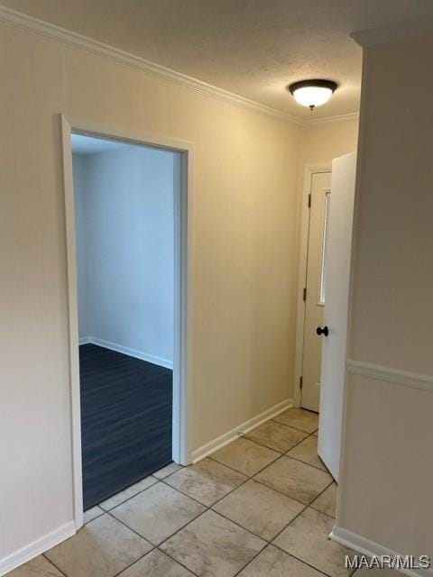 hall with ornamental molding, baseboards, and light tile patterned floors