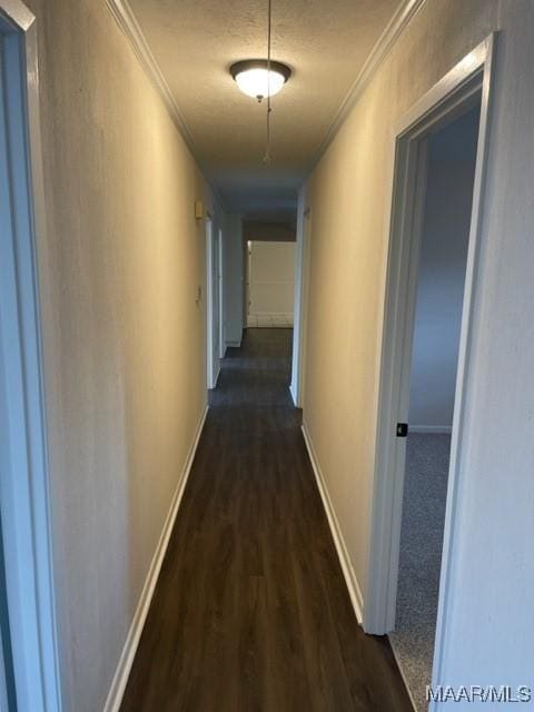 corridor with ornamental molding, dark wood-style flooring, and baseboards