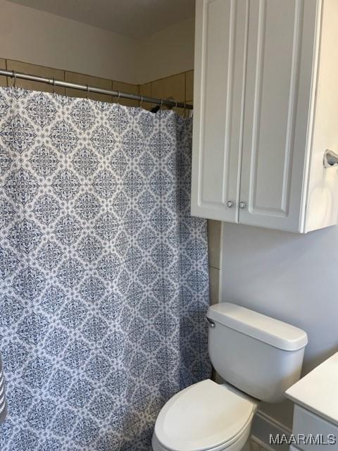 full bath with a shower with curtain, vanity, and toilet