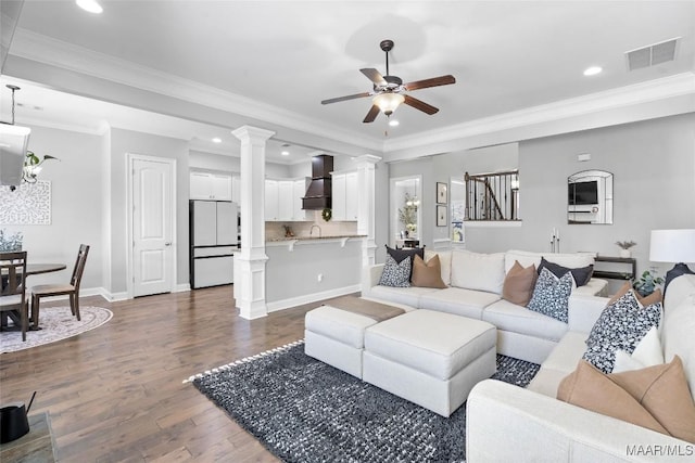 living room featuring visible vents, baseboards, dark wood-style floors, ceiling fan, and ornate columns