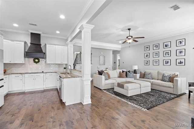 living area with ornate columns, ceiling fan, visible vents, and dark wood-style flooring