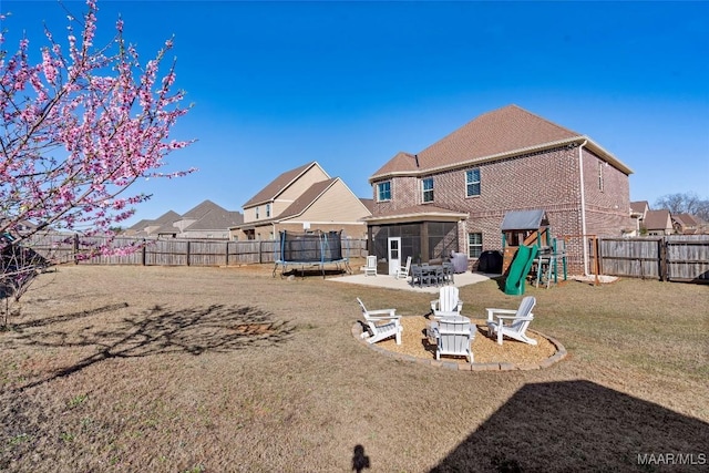 back of property featuring a sunroom, a fenced backyard, a trampoline, a patio area, and brick siding