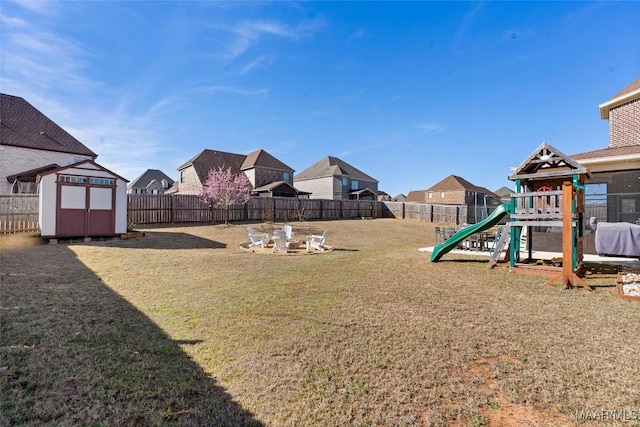 view of yard featuring a fenced backyard, a storage unit, and an outbuilding