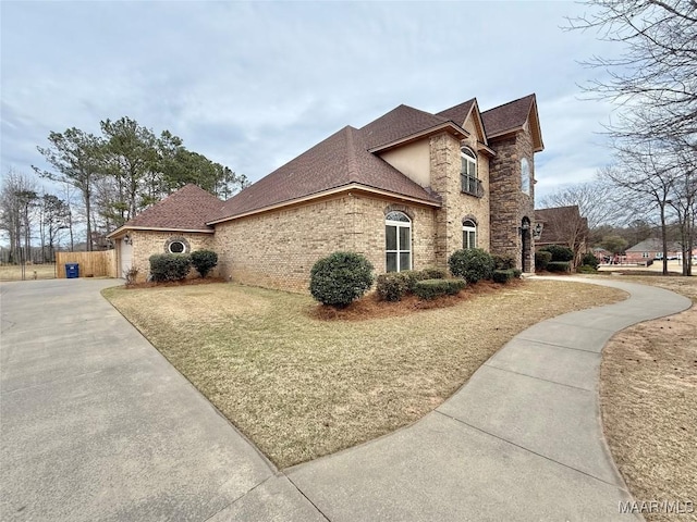 view of property exterior featuring driveway, a shingled roof, and brick siding