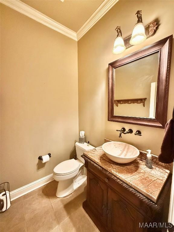 half bath featuring crown molding, toilet, vanity, baseboards, and tile patterned floors