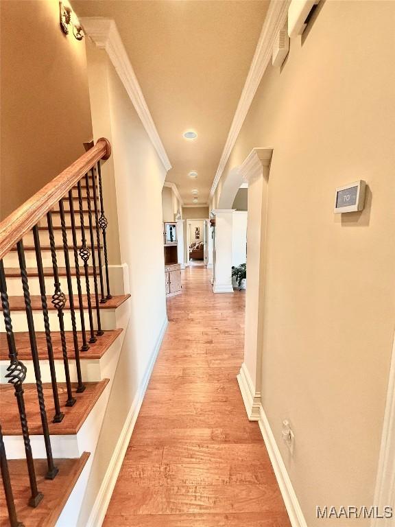 corridor with crown molding, light wood-type flooring, and baseboards