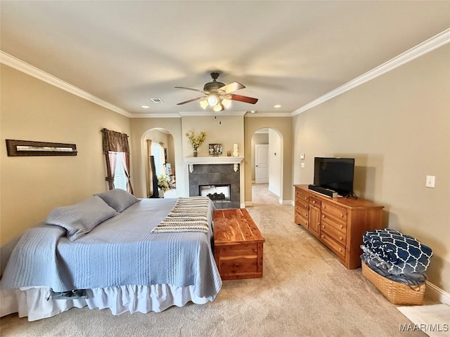 bedroom featuring light carpet, visible vents, arched walkways, ornamental molding, and a fireplace