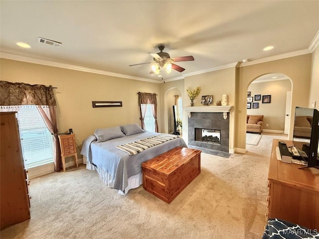 bedroom with light carpet, arched walkways, multiple windows, and visible vents