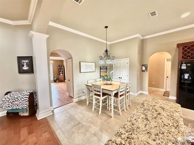 dining area with light wood-style floors, visible vents, arched walkways, and crown molding