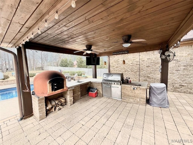 view of patio / terrace featuring a ceiling fan, fence, grilling area, and exterior kitchen