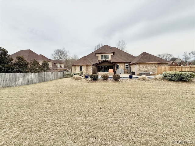 back of property with a lawn, a patio area, and fence