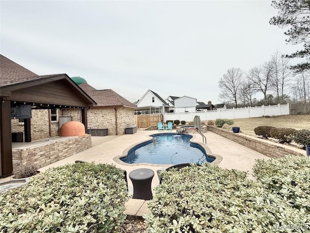 view of swimming pool with exterior kitchen, a patio area, a fenced backyard, and a fenced in pool