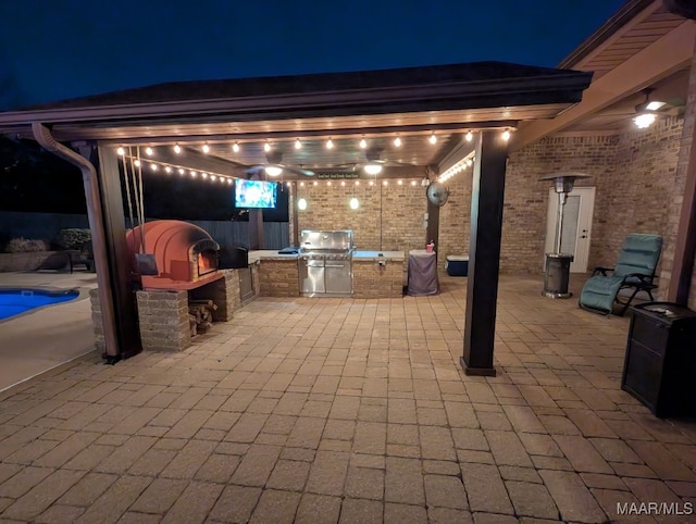 patio at night with area for grilling and an outdoor kitchen