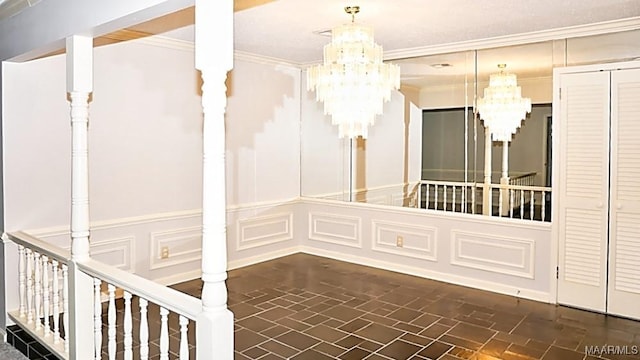 empty room featuring ornamental molding, brick floor, a notable chandelier, and a decorative wall