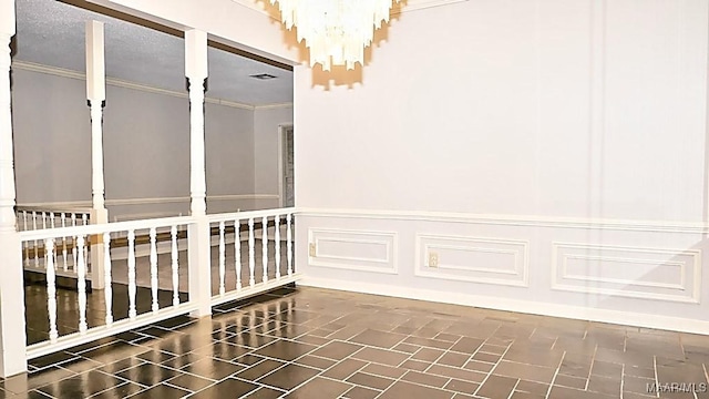 interior space featuring a textured ceiling, a decorative wall, ornamental molding, wainscoting, and an inviting chandelier