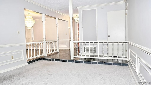 interior space featuring a wainscoted wall, ornamental molding, a textured ceiling, a chandelier, and a decorative wall