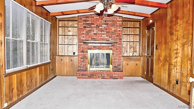 unfurnished living room with carpet floors, a brick fireplace, visible vents, and wooden walls