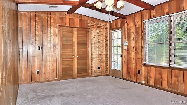 carpeted spare room with ceiling fan, lofted ceiling with beams, and wooden walls