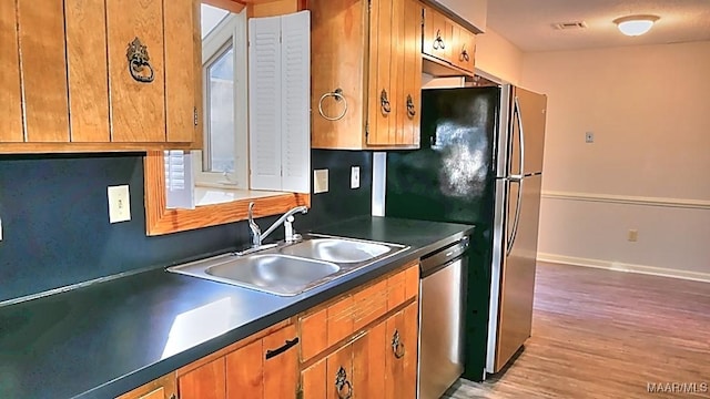 kitchen featuring a sink, visible vents, baseboards, stainless steel dishwasher, and dark countertops