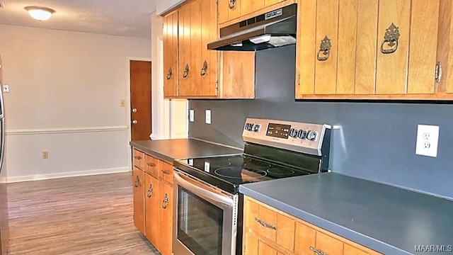 kitchen with baseboards, dark countertops, light wood-style flooring, stainless steel electric stove, and under cabinet range hood