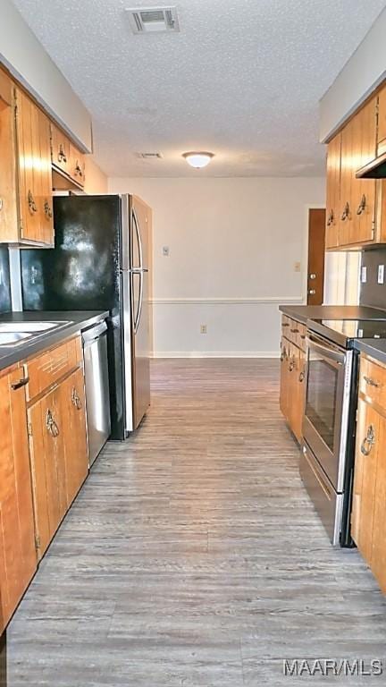 kitchen with visible vents, dark countertops, appliances with stainless steel finishes, a textured ceiling, and light wood-type flooring