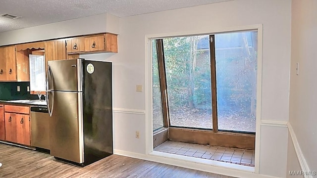 kitchen with light wood finished floors, visible vents, appliances with stainless steel finishes, a textured ceiling, and a sink