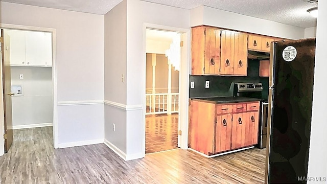 kitchen featuring stainless steel range with electric stovetop, dark countertops, light wood-style flooring, and a textured ceiling