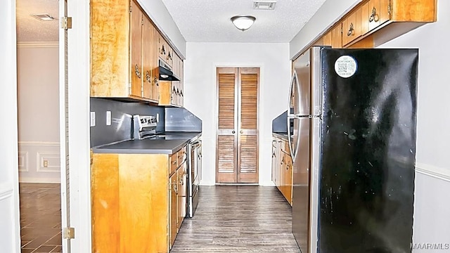 kitchen with a textured ceiling, appliances with stainless steel finishes, visible vents, and under cabinet range hood