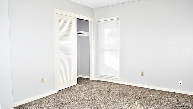 unfurnished bedroom with a closet, carpet, and baseboards